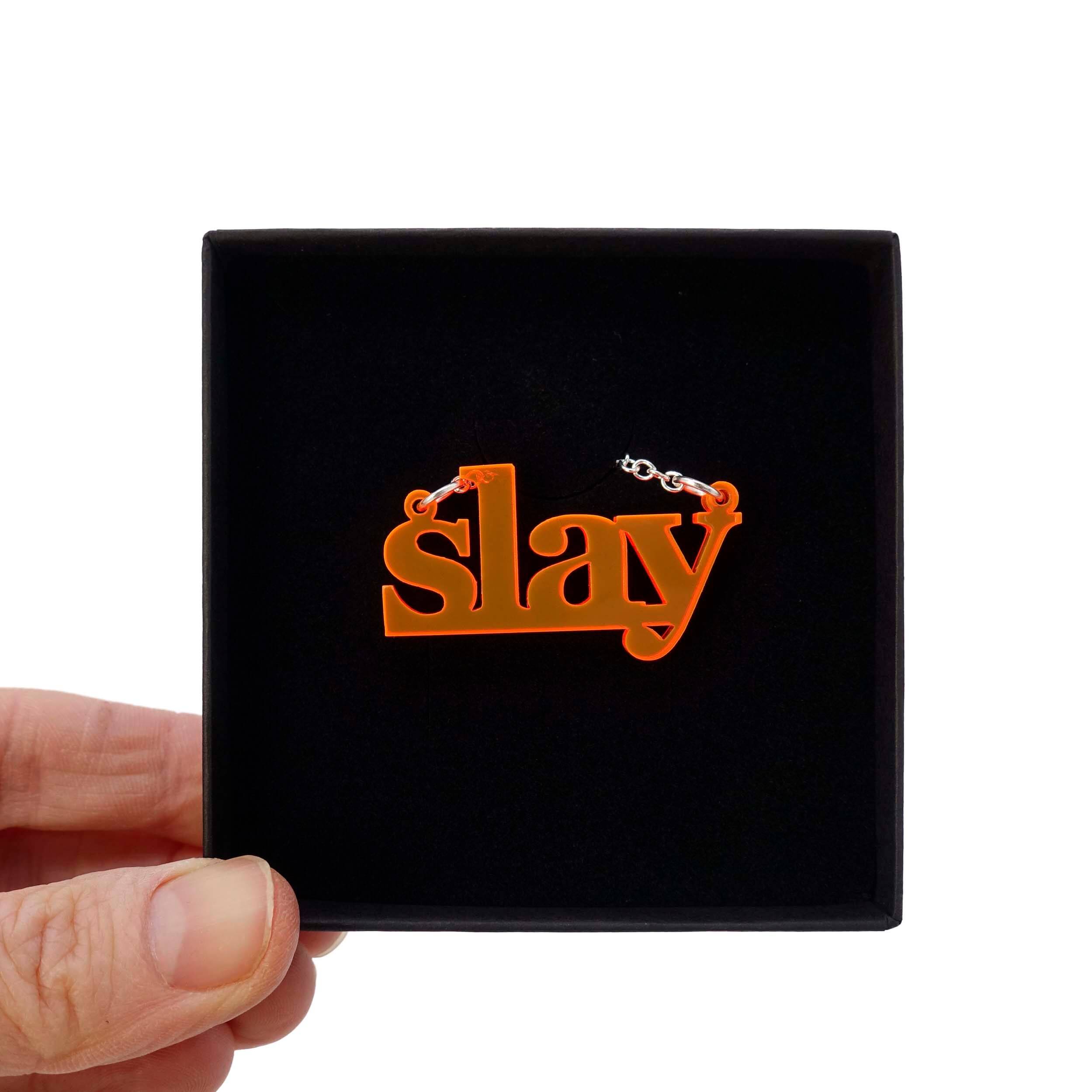 Fluorescent orange slay necklace shown being held up in a gift box. 