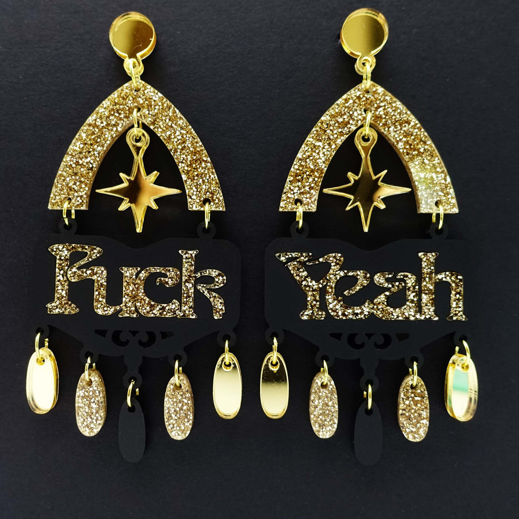 Fuck yeah earrings in black and gold glitter shown hanging on black background