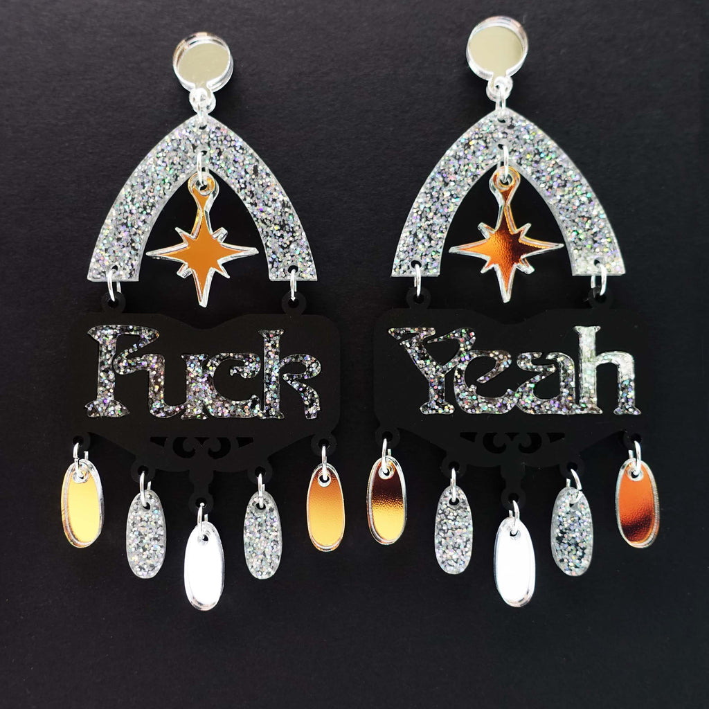 Fuck yeah earrings in black and iridescent silver glitter shown hanging on black background]