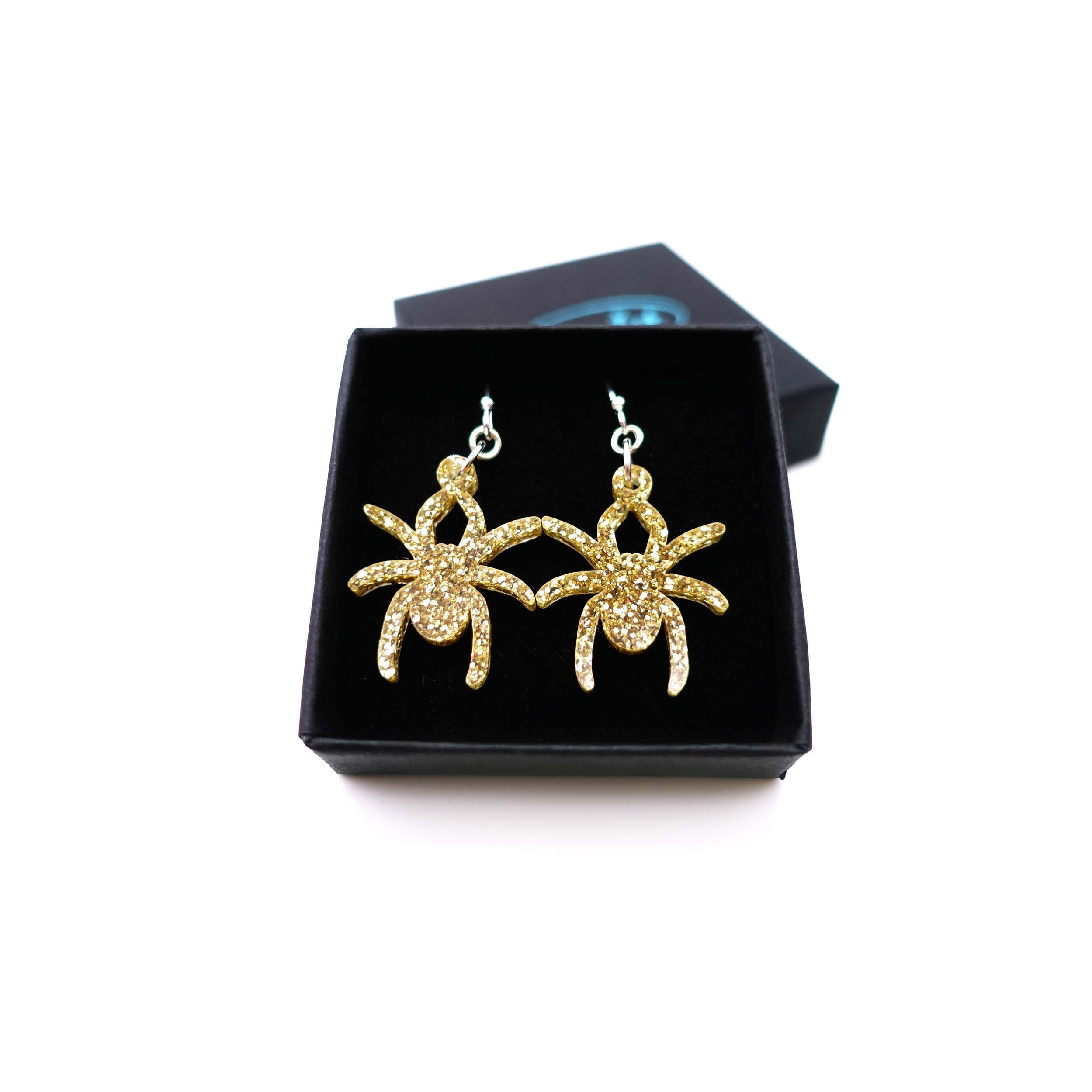 Lady Hale commemorative spider earrings in gold glitter shown in box.