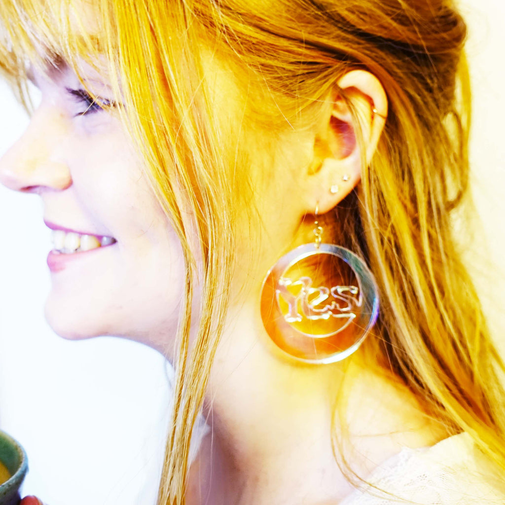 Model smiles wearing Hell Yes earrings by Wear and Resist, handmade in Sarah Day's Oxfordshire studio. 