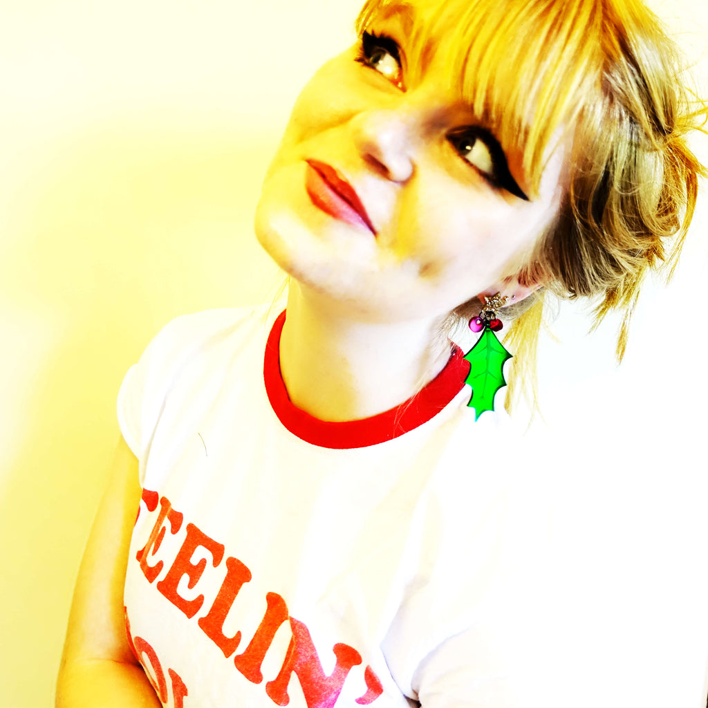 Model wears Christmas Holly statement earrings by Wear and Resist. 
