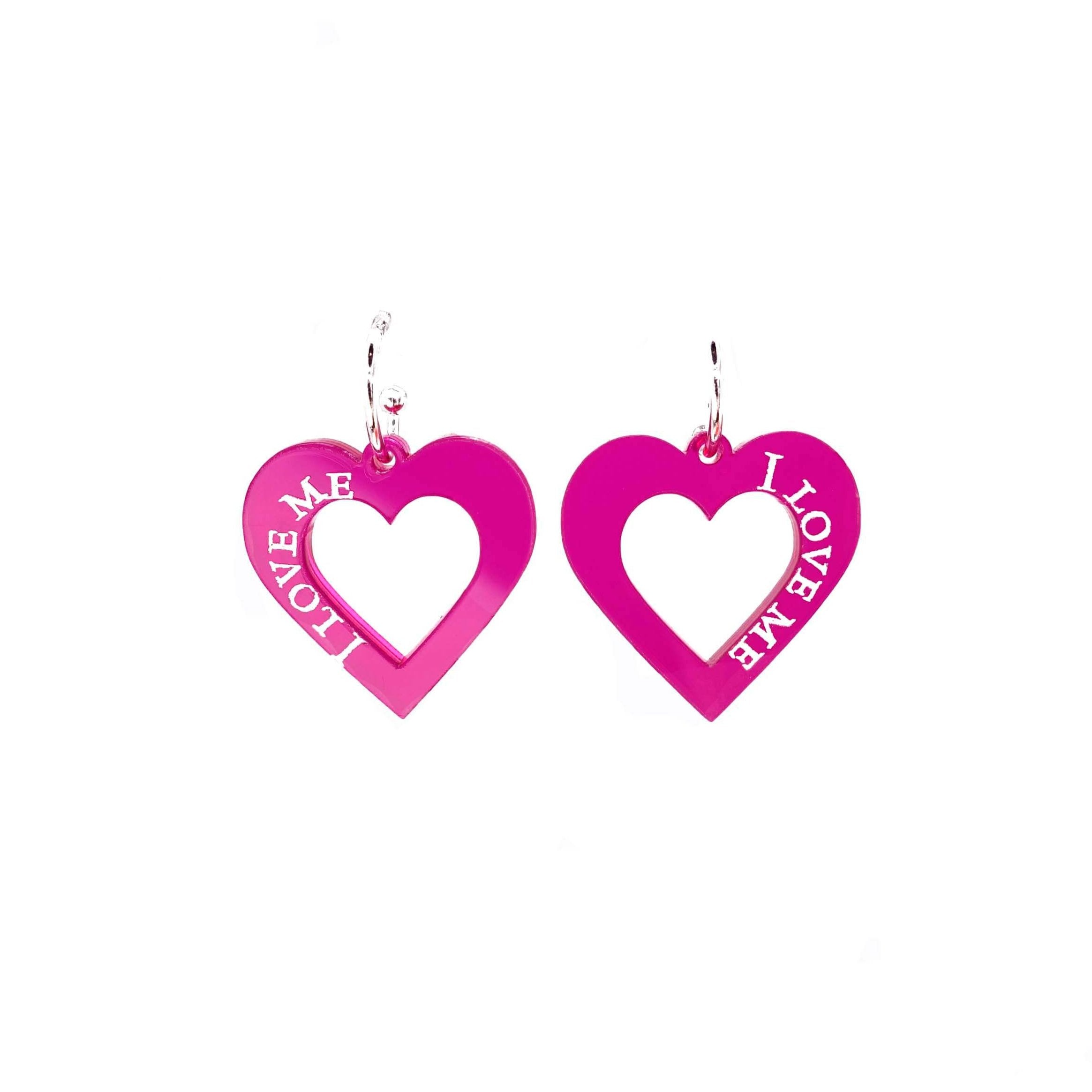 Neon pink I love me heart hoops shown hanging on a white backround.