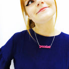 Eliza wears a hot pink typerwriter font Persist necklace. 