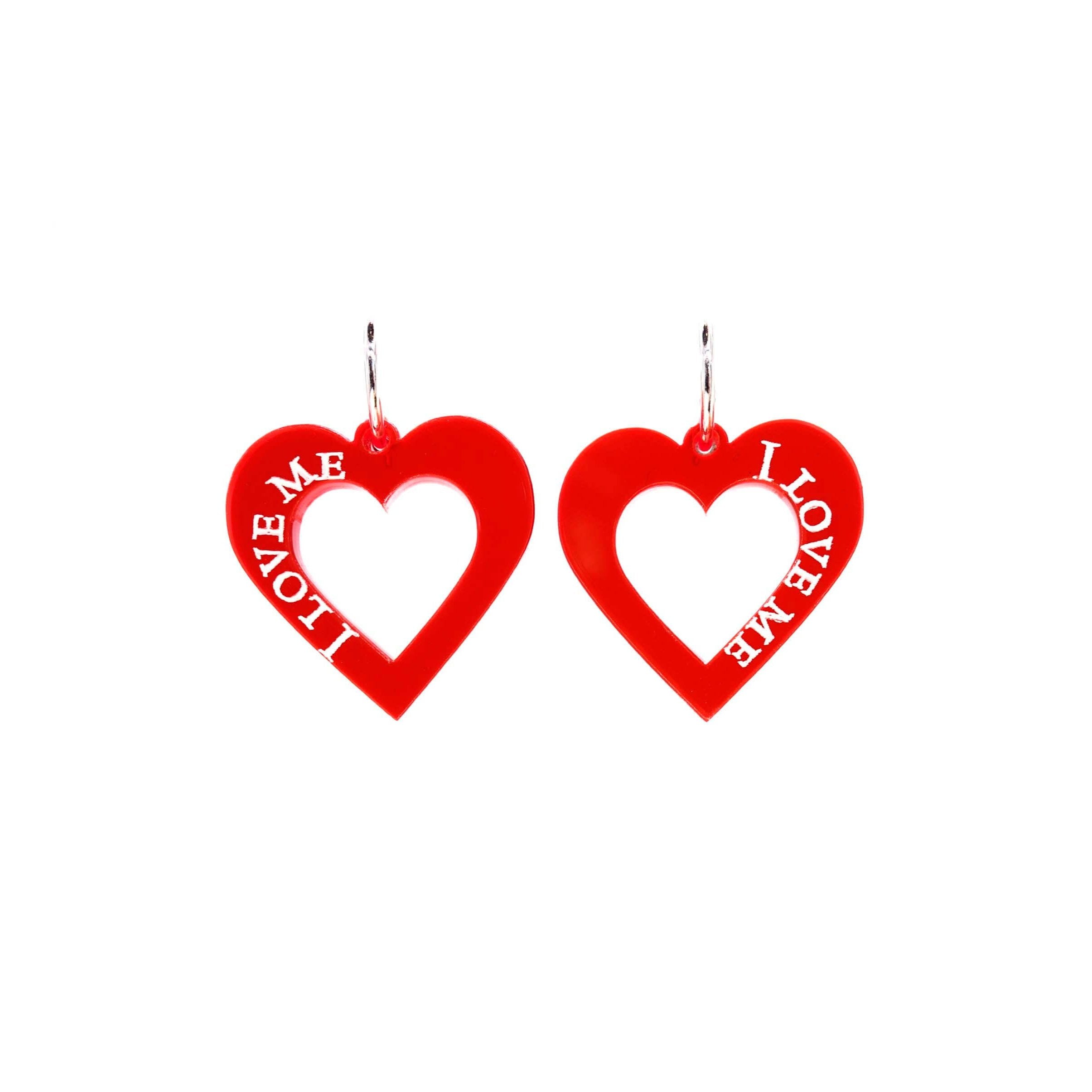 Hot red heart earrings etched with the words, I love me, on silver plated hoops, shown against a white background. 