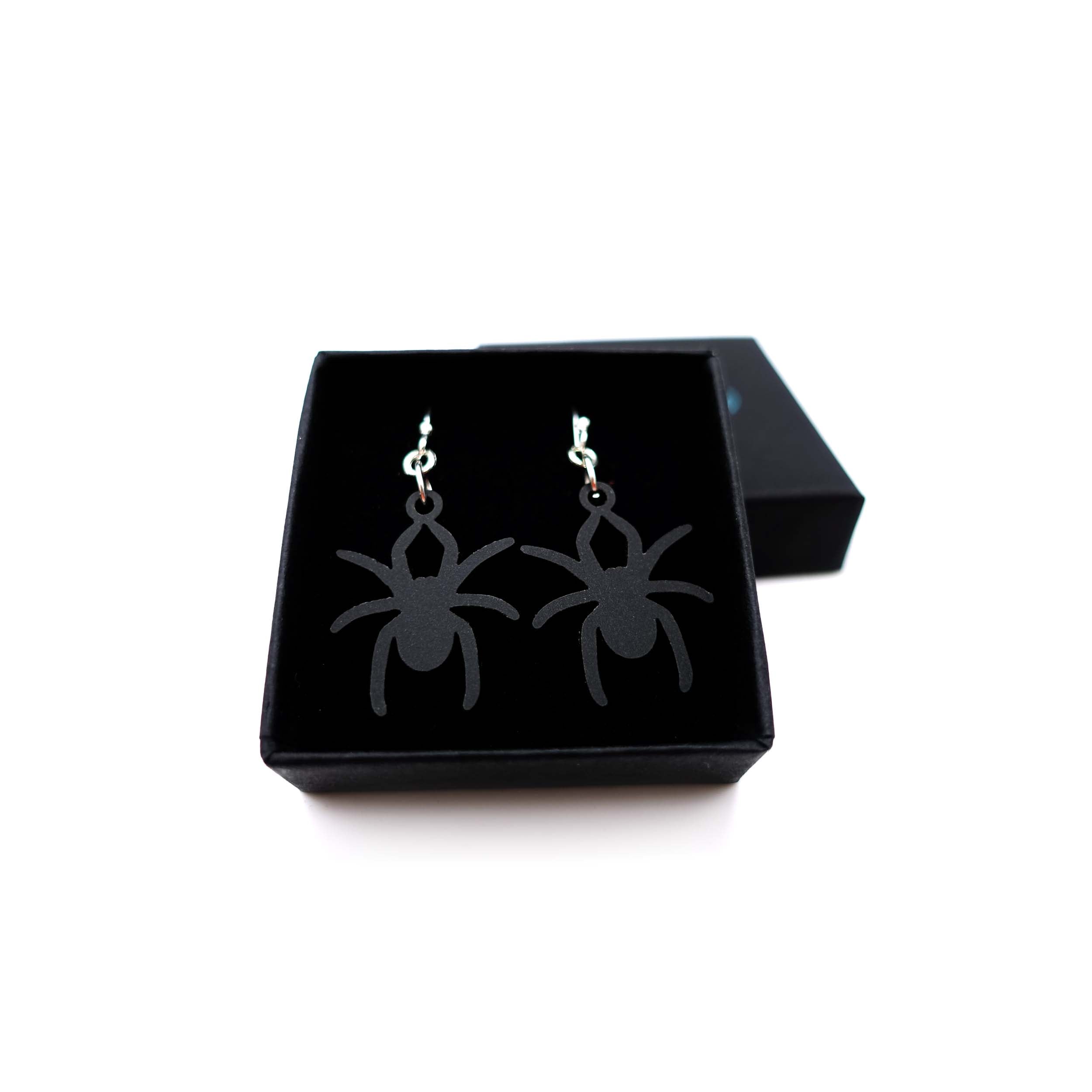Lady Hale commemorative spider earrings in matte black shown in box.