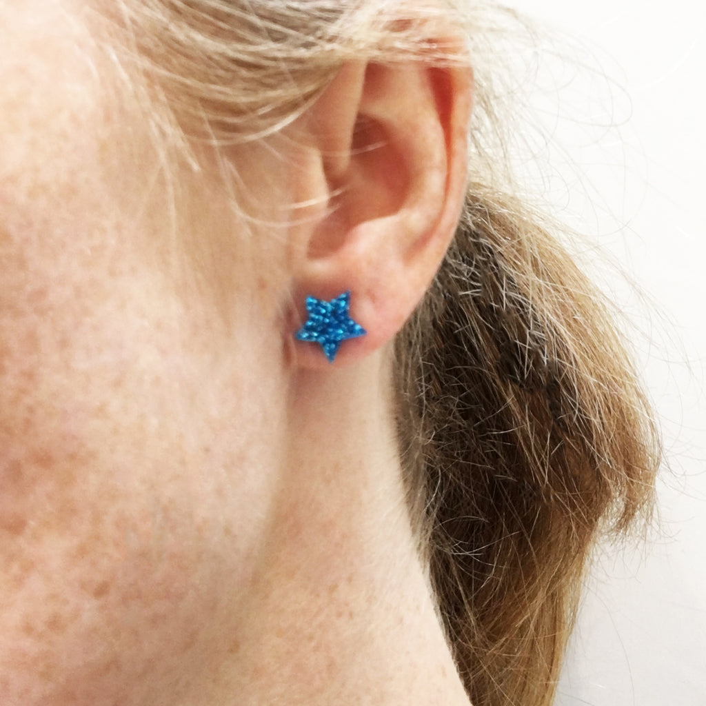 model wears blue glitter small star earrings