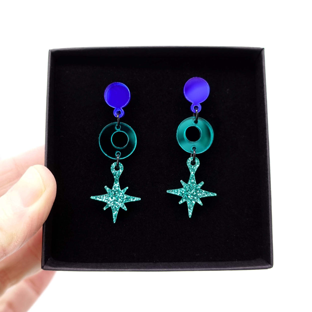 Deco Star drop earrings in Midnight colours shown being held up in gift box. 