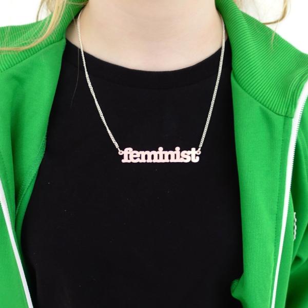 Eliza wears a shell pink Feminist necklace. 