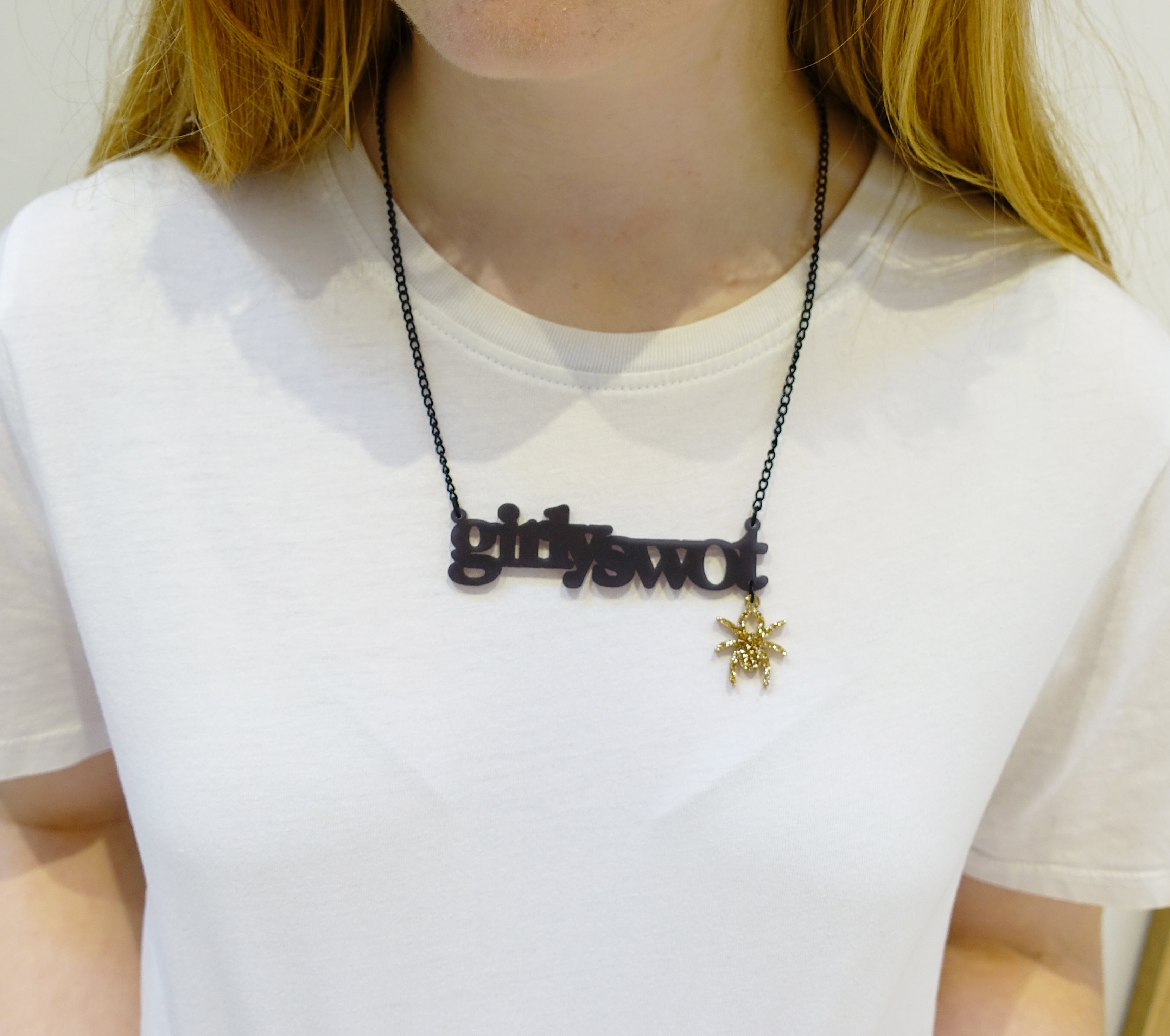 Eliza wears slate Girly Swot necklace with hanging Lady Hale spider. 