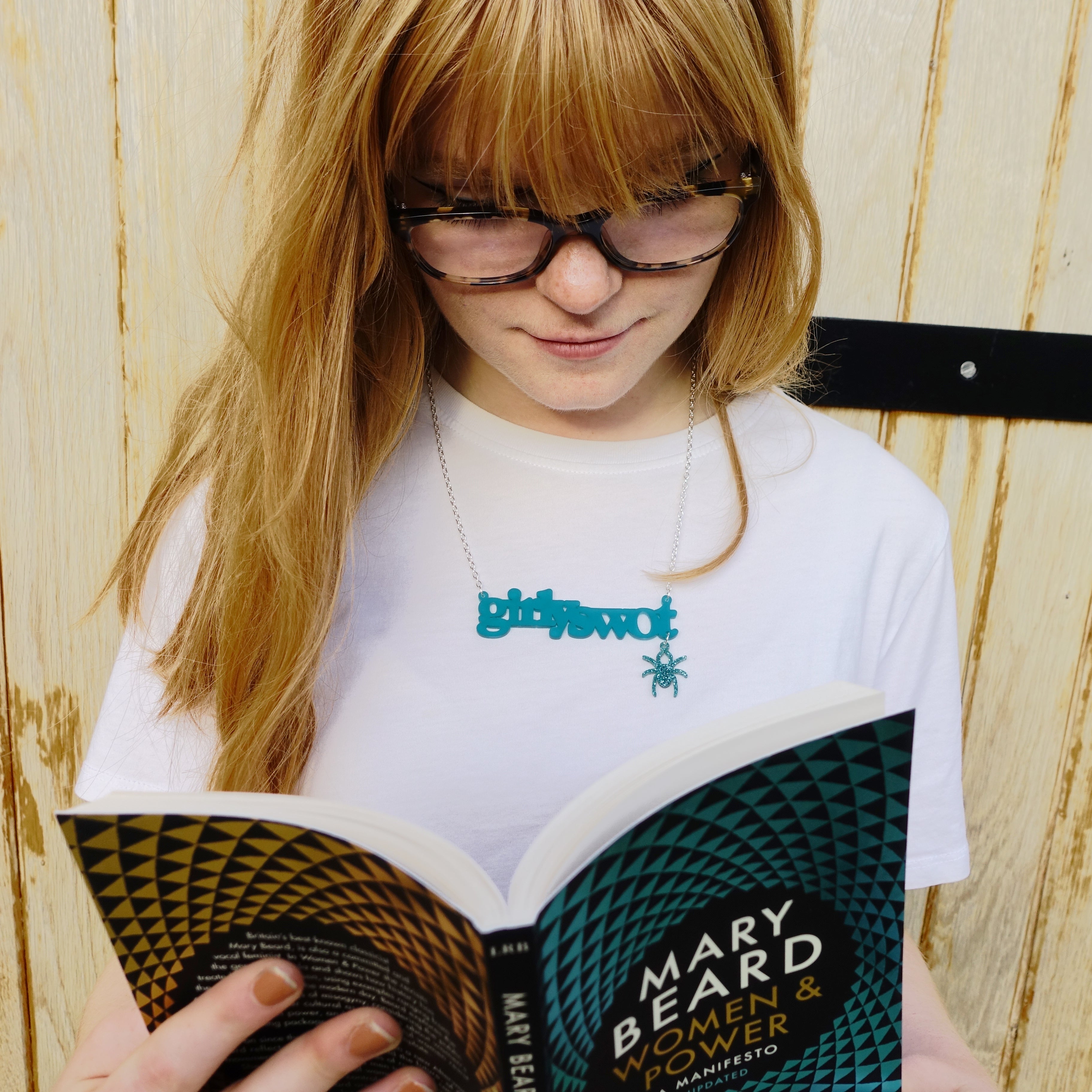 Eliza wears teal Girly swot necklace with hanging Lady Hale spider and reads Mary Beard's Women & Power. Girly swots unite! 