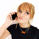 Eliza wears a fluoro orange Slay necklace as she slays on the phone. 