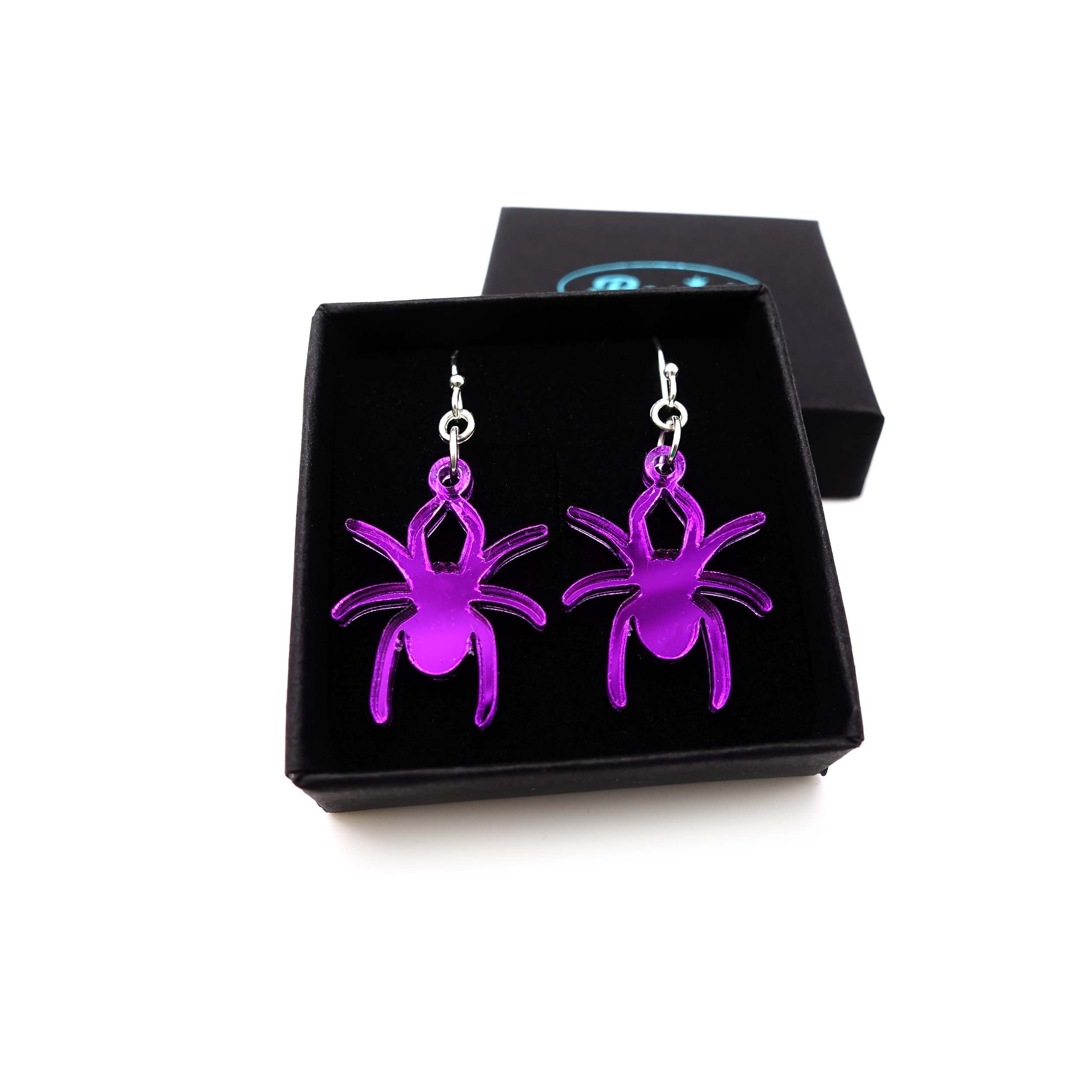 Lady Hale commemorative spider earrings in poison purple shown in box.