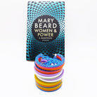Stack of three colour choices of Power earrings in front of paperback edition of Mary Beard 's Women & Power  