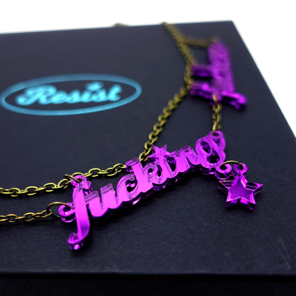 Poison lies F*ck These F*cking F*ckers necklace shown close up on a Wear and Resist large gift box. 