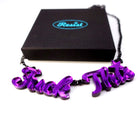 A purple mirror F*ck This necklace shown with a Wear and Resist gift box. 