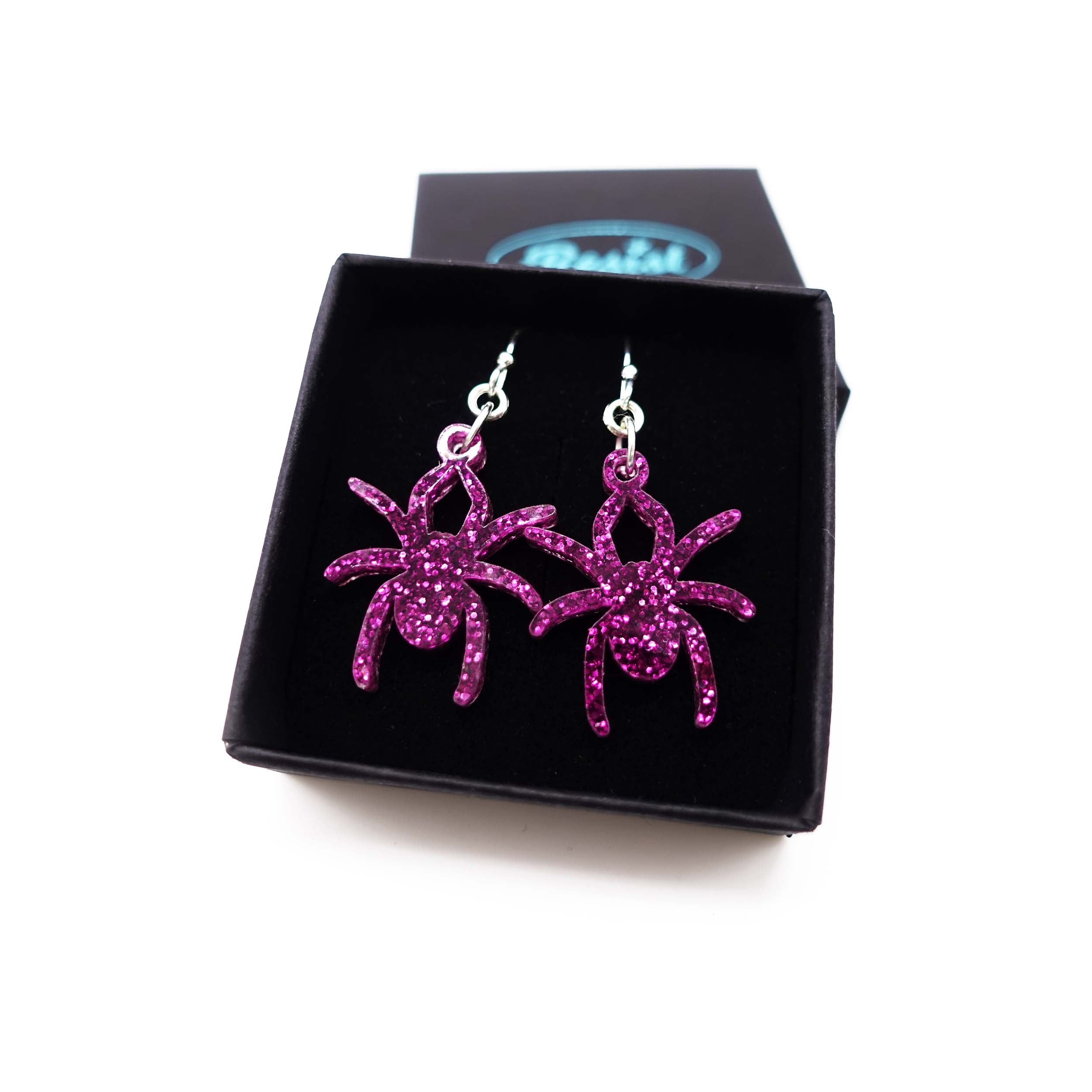 Lady Hale commemorative spider earrings in purple glitter  shown in box.