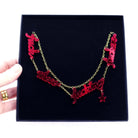 Rose garden red  F*ck These F*cking F*ckers necklace shown in a Wear and Resist large gift box held up.  