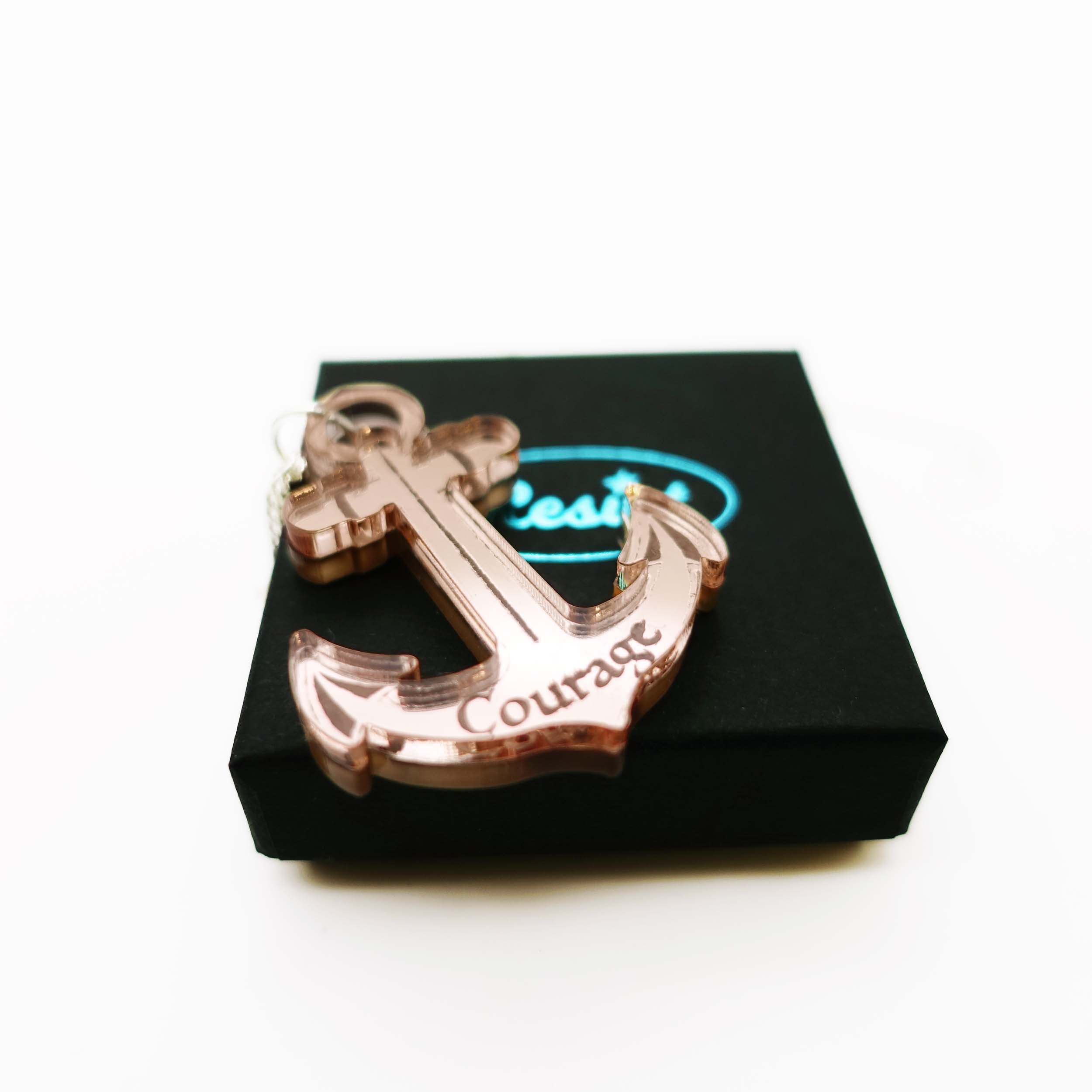 Rose-gold engraved courage anchor pendant shown on the small gift box. £4 from the sale of each will be split equally between the RNLI and Women for Refugee Women. 