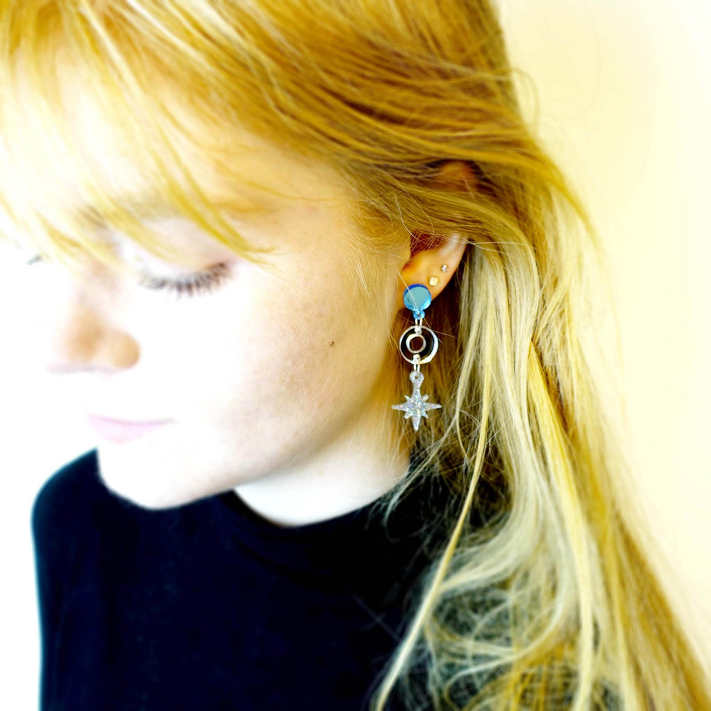 Model wears cool silver Deco Star drop earrings. 