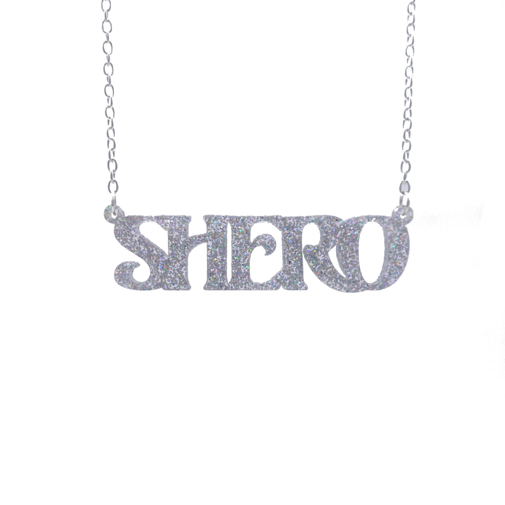 Silver glitter Shero necklace hanging against a white background. 