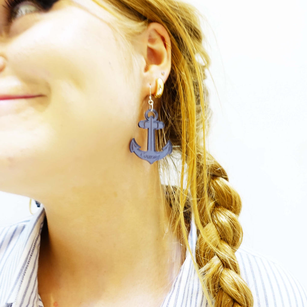 Model laughing wearing slate etched anchor earrings this one engraved with Courage, made by Wear and Resist with proceeds gong to support the RNLI and Women for Refugee Women. 