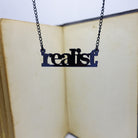 realist literary necklace hanging in front of book