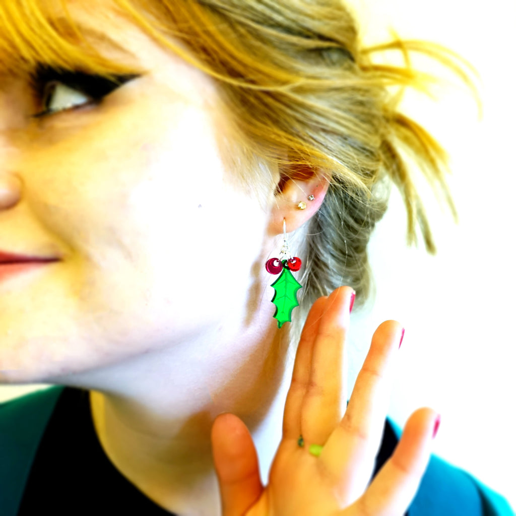Model wears small dangly Holly earrings with red berries on sterling silver wire fish hooks. 