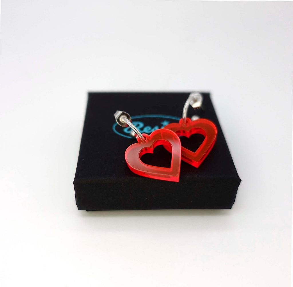 Hot red transparent small love heart earrings shown on a Wear and Resist gift box. 