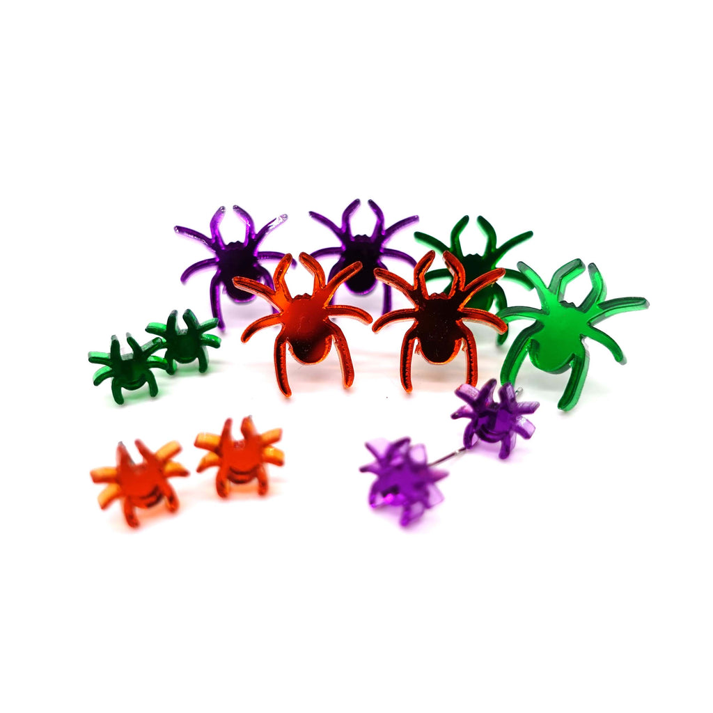 Tiny spiders and spider stud earrings shown together in a group shot. 