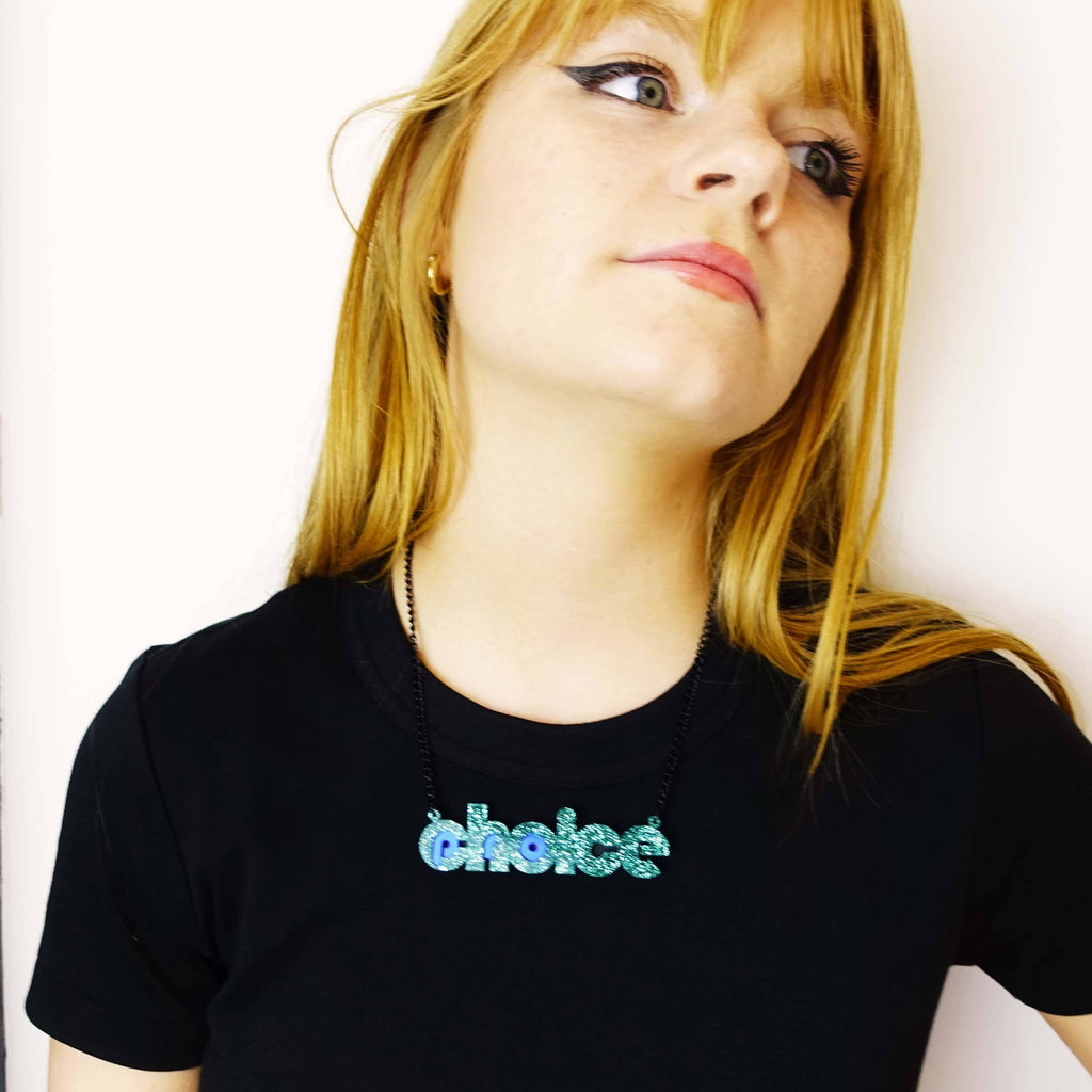 Model wears teal glitter pro-choice necklace, designed by Sarah Day for Wear and Resist. 