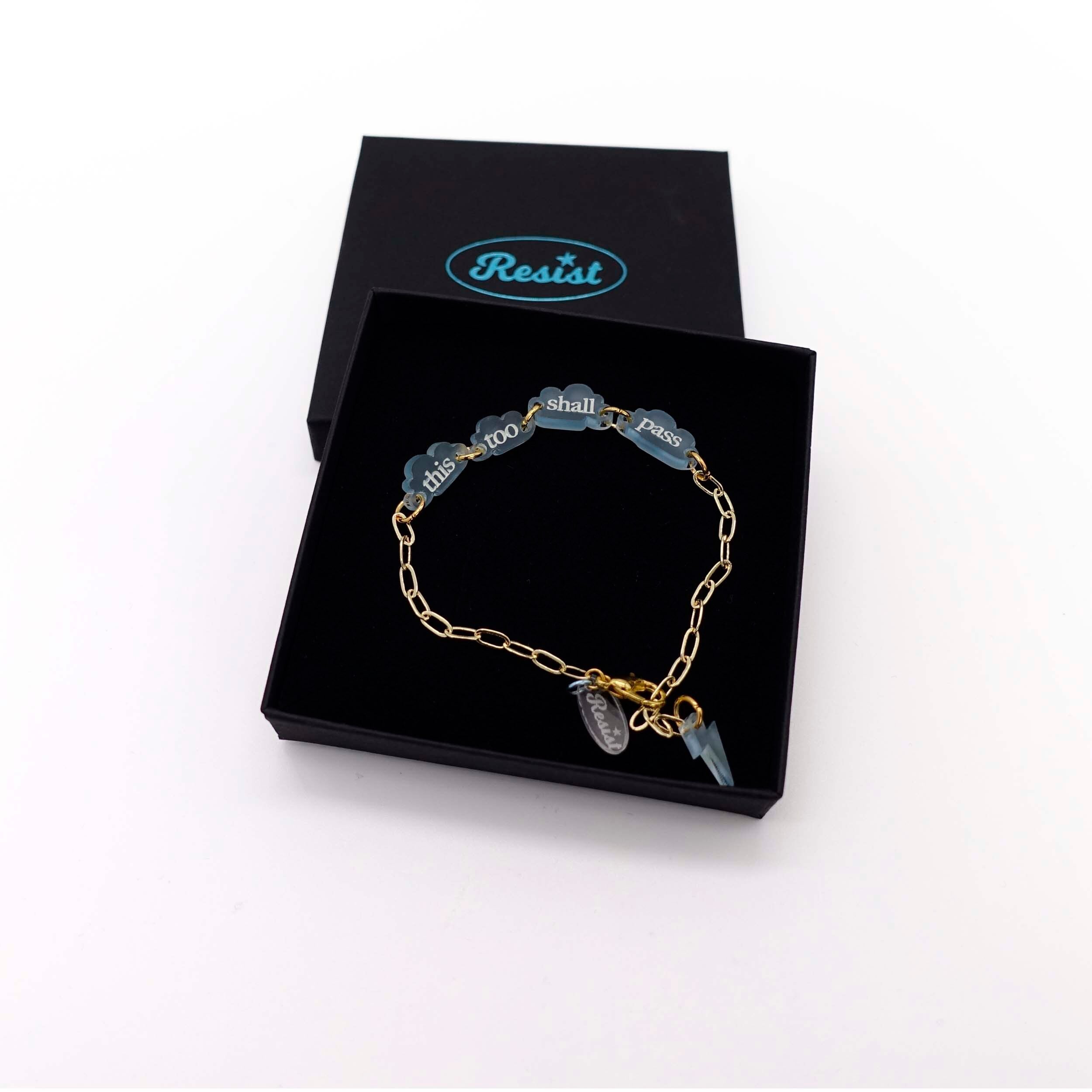 This too shall pass floating clouds gold-plated paper-clip  bracelet shown in a Wear and Resist gift box. 