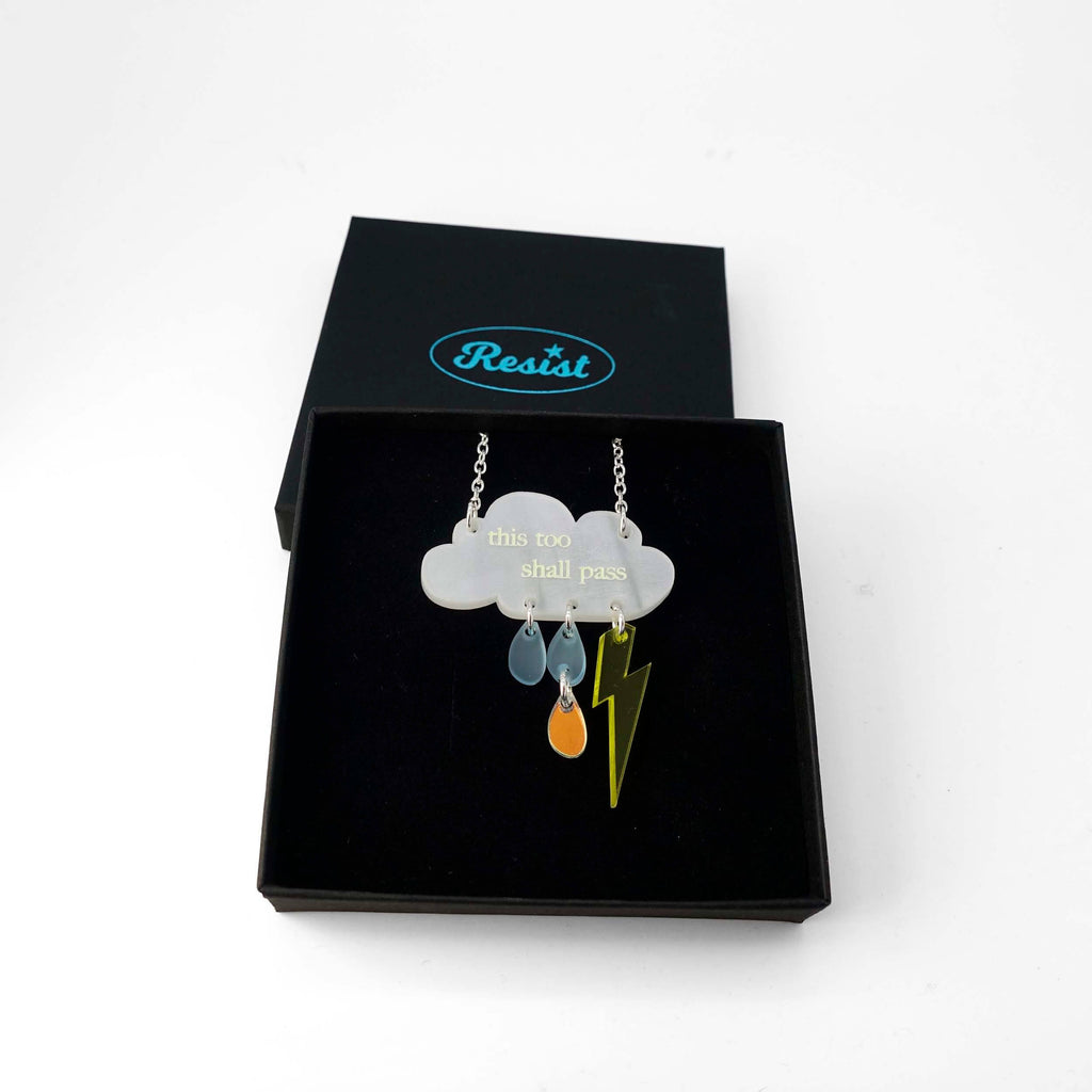 This too shall pass glow-in-the-dark raincloud necklace designed by Sarah Day for Wear and Resist. Shown in a gift box. £2 goes to Woman's Trust charity. 