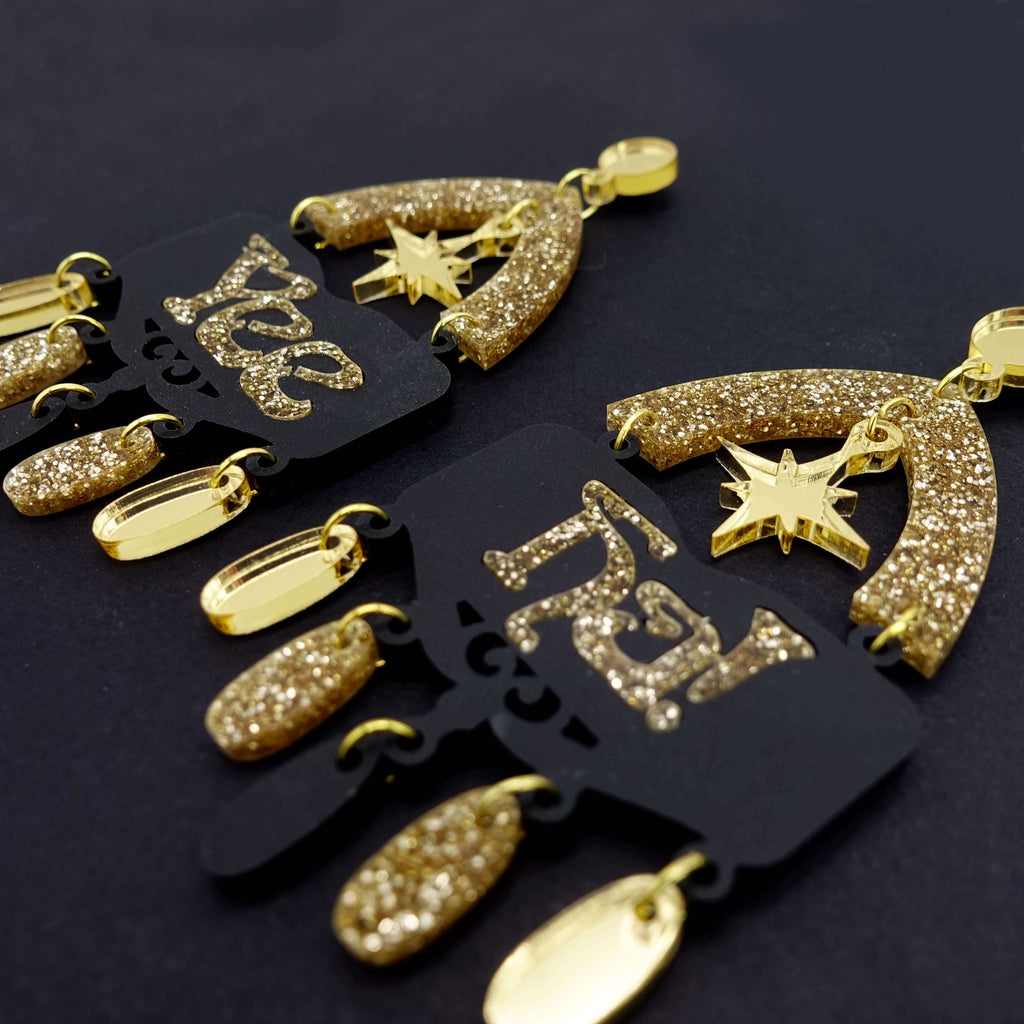 Yee Ha statement earrings in gold glitter by Wear and Resist, shown on a black background. Earrings for going OUT out! 